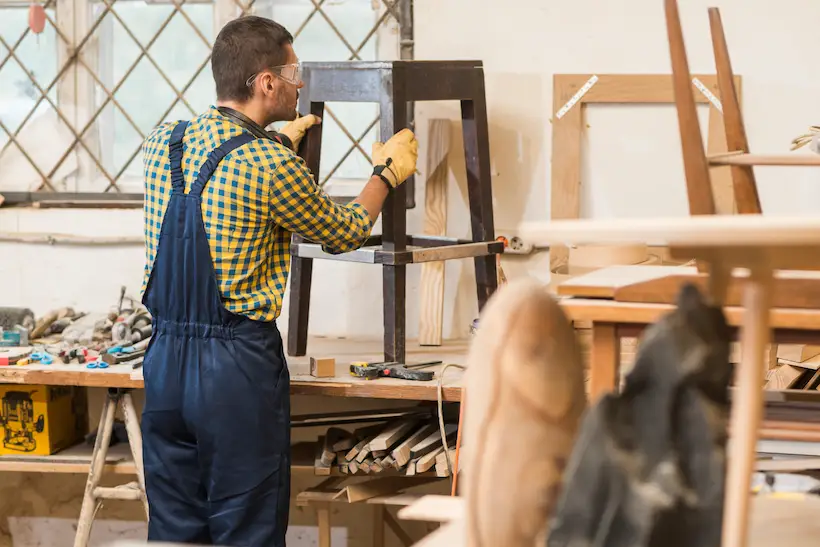 A hobbyist in a small workshop, mid-build, surrounded by offcuts and tools — tying sustainability back to the maker community.