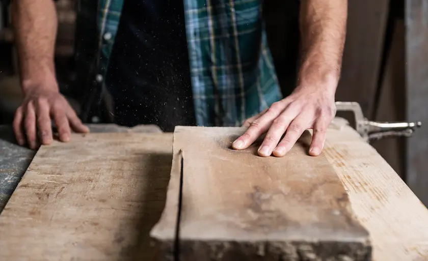 Woodworker's hands cutting piece of timber on a bench
